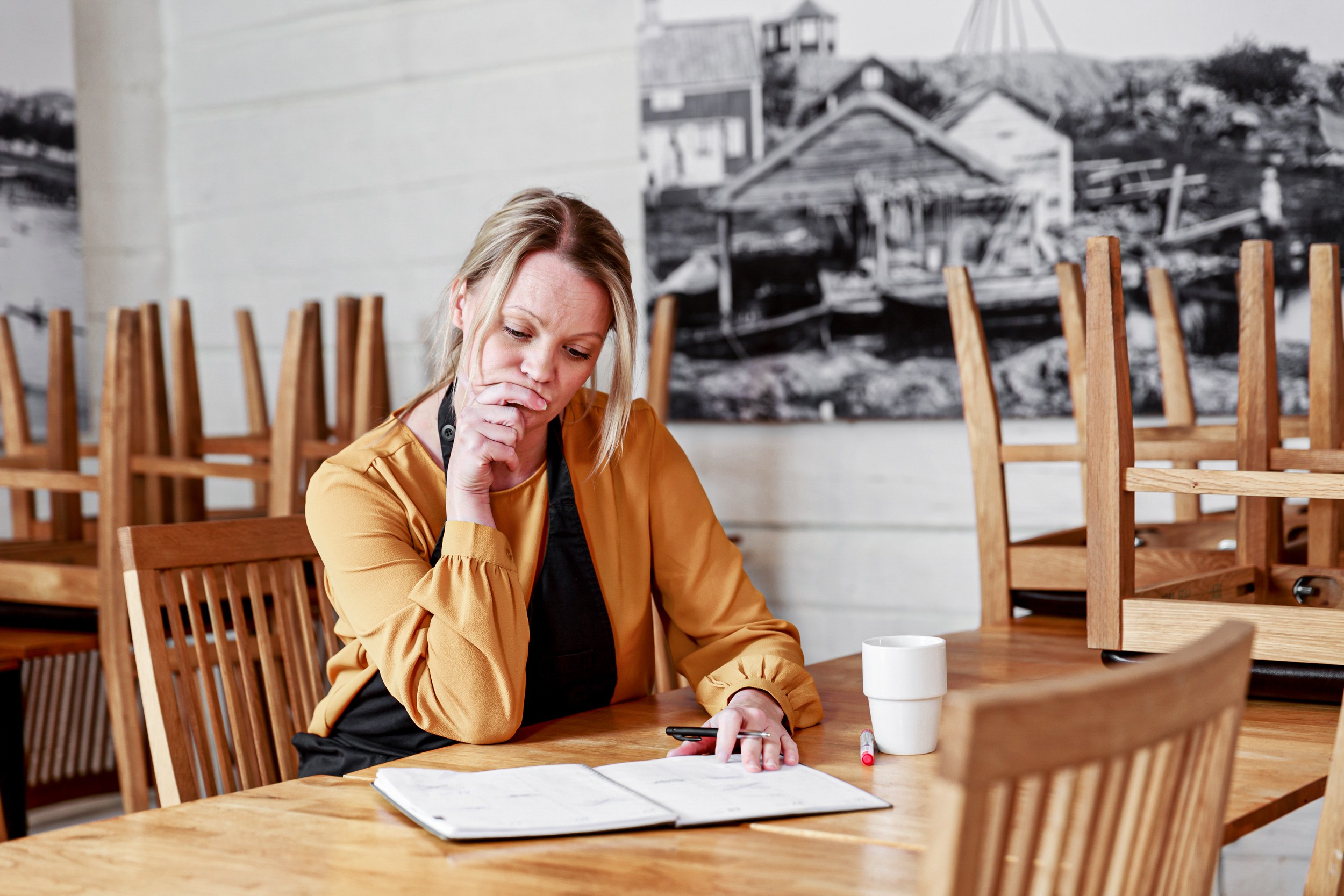En kvinna sitter vid ett bord och skriver i en anteckningsbok. 