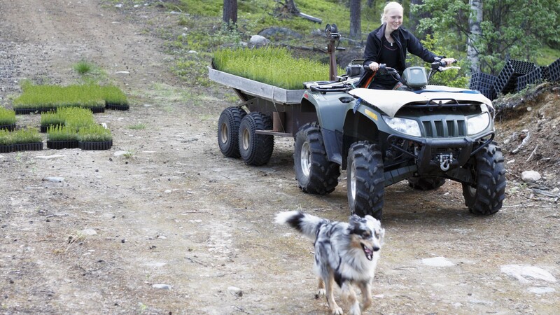 Woman on quad bike with dog running next to her