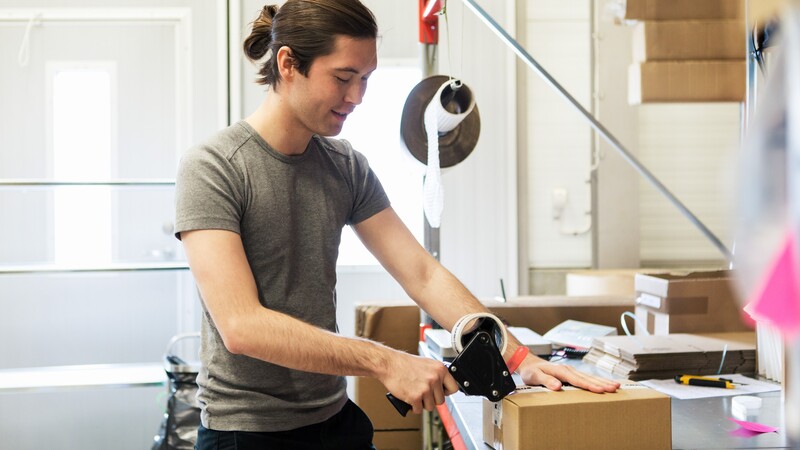 Young man tapes up a package