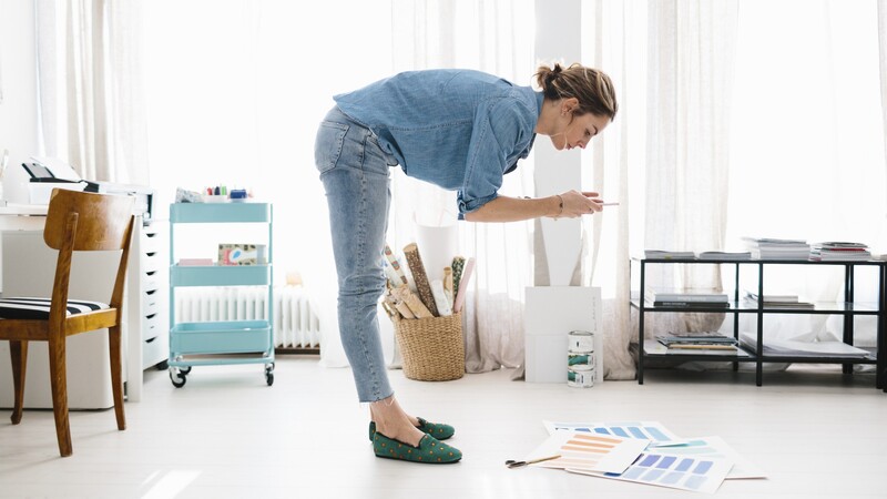 Woman bent forward photographing paper on the floor