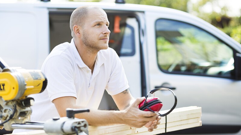 a male carpenter leaning on saw