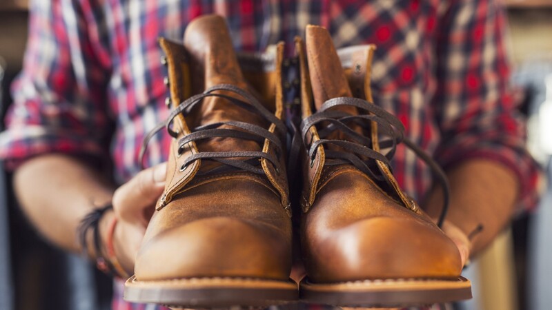 Hands holding up a pair of leather boots