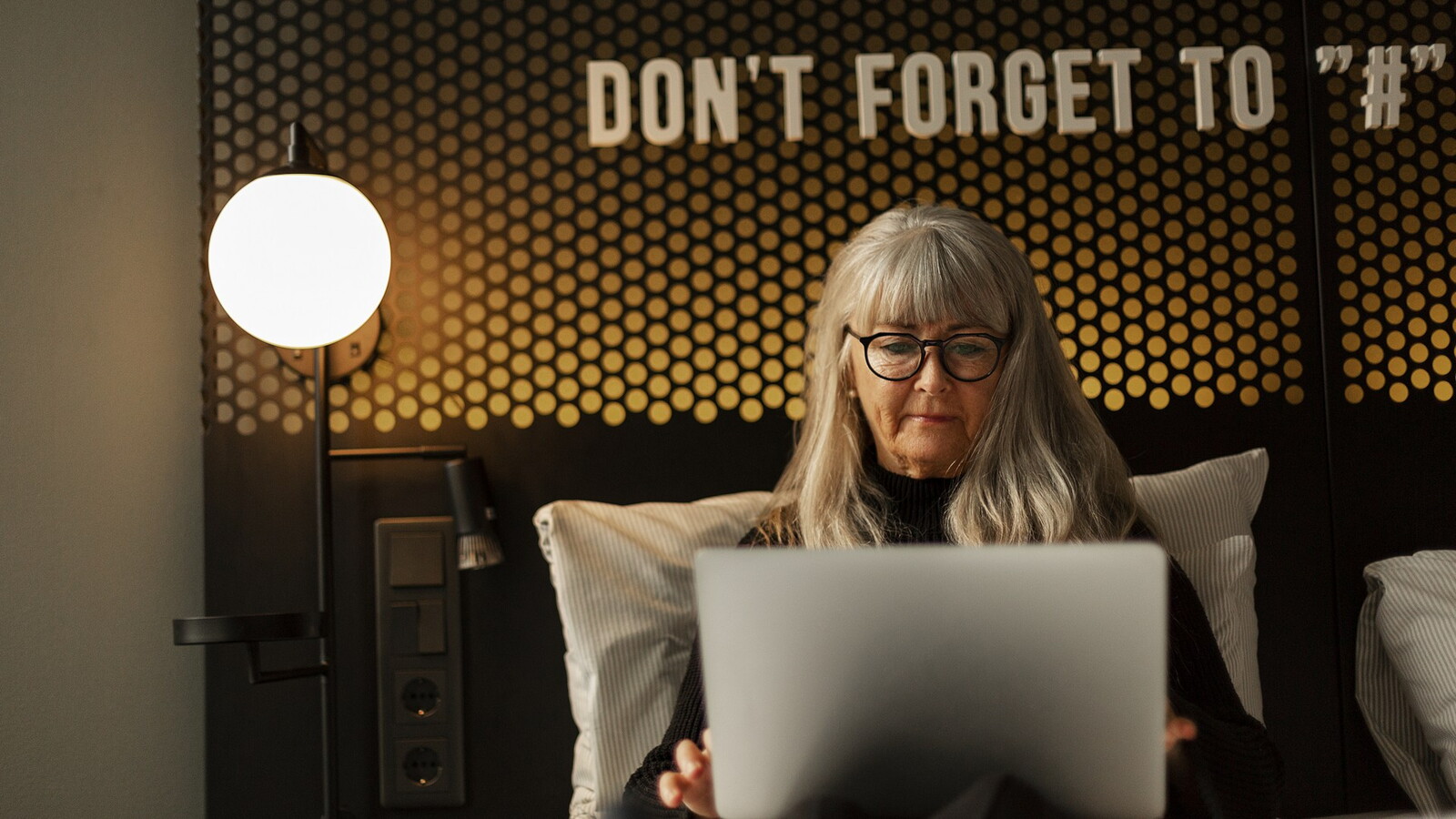 Kvinna sitter med laptop i hotellsäng