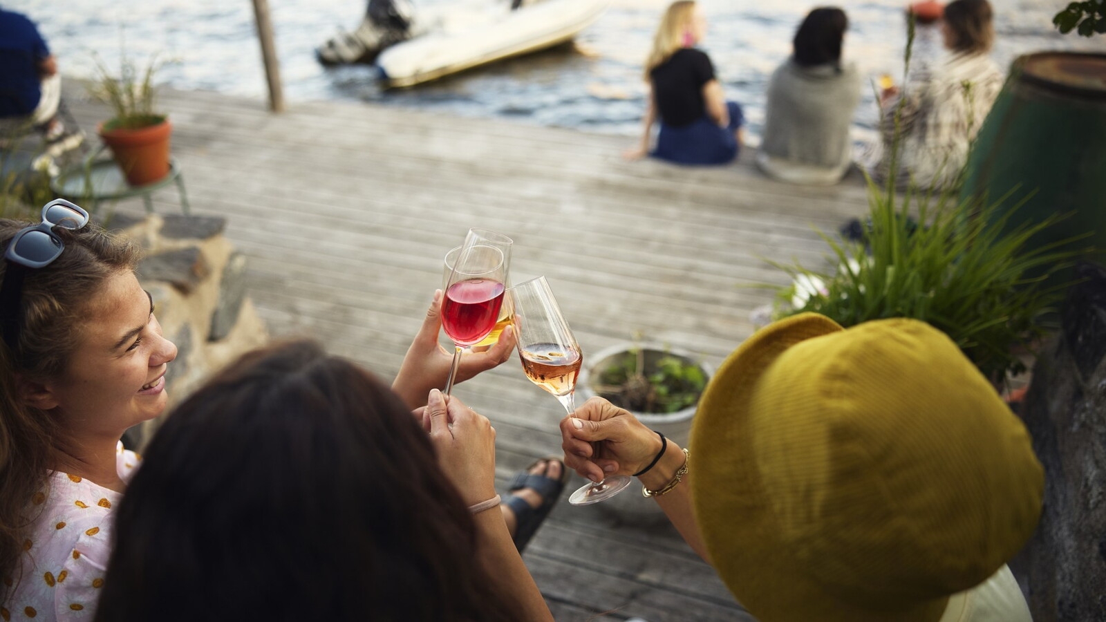 Personer skålar i vin på en brygga