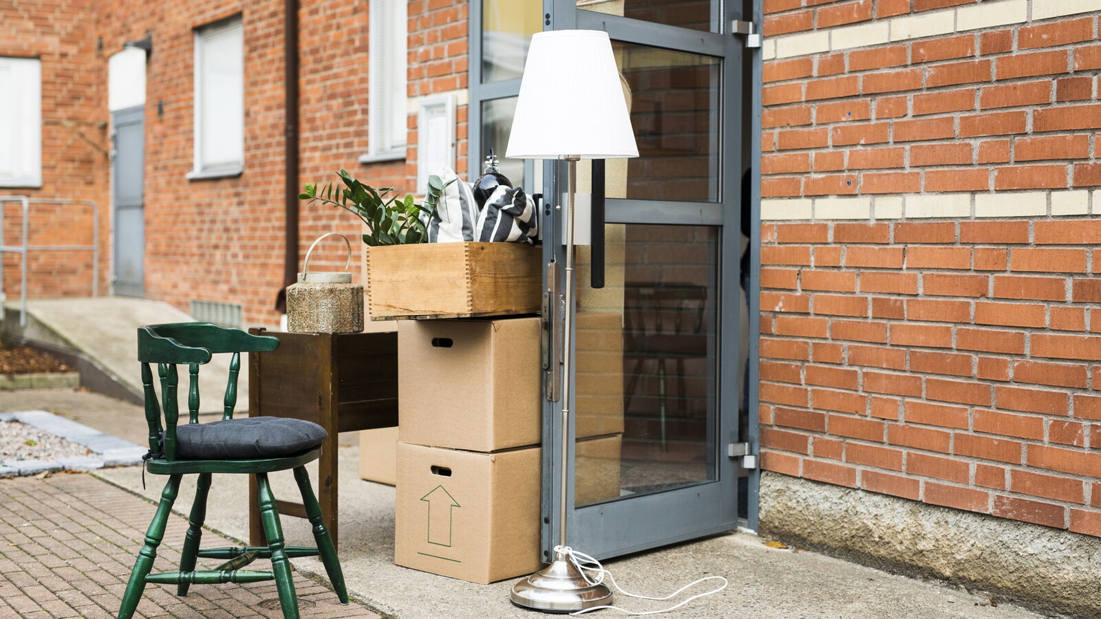 Flyttlådor, stol och lampa utanför en byggnad